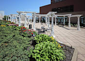 Thumbnail 11 of 13 - A white pergola is over a patio with tables and chairs.