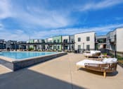 Thumbnail 10 of 13 - A pool area with a sun lounger and a building in the background.
