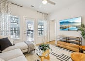 Thumbnail 4 of 140 - Modern living room with media console and ceiling fan at Matador Apartments, Austin, 78745