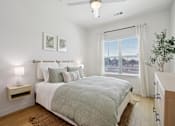 Thumbnail 55 of 116 - A bedroom with a bed, nightstand, and a plant. at Park South Apartments, Austin