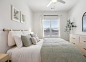 Thumbnail 58 of 116 - A bedroom with a large bed, a ceiling fan, and a window with blinds. at Park South Apartments, Austin, TX
