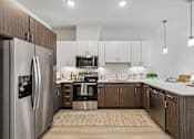 Thumbnail 39 of 127 - A modern kitchen with a refrigerator on the left and a sink in the middle.