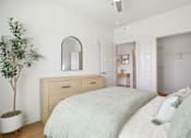 Thumbnail 61 of 116 - A bedroom with a bed, dresser, mirror, and a plant. at Park South Apartments, Texas