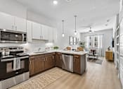 Thumbnail 42 of 127 - A modern kitchen with a stove, microwave, and oak cabinets.