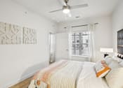 Thumbnail 21 of 140 - Bright bedroom with ceiling fan and large window at Matador Apartments, Austin
