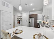 Thumbnail 44 of 127 - A modern kitchen with a dining table set for two.