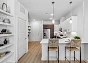Thumbnail 46 of 127 - A kitchen with a white island and two chairs.