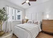 Thumbnail 48 of 127 - A bedroom with a white bed and a wooden dresser.