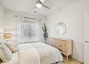 Thumbnail 26 of 140 - Bright bedroom with wood dresser and round mirror at Matador Apartments, Austin