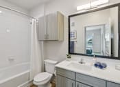 Thumbnail 69 of 116 - A bathroom with a white toilet, a white sink, and a large mirror. at Park South Apartments, Texas