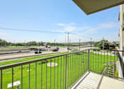 Thumbnail 71 of 116 - A balcony overlooks a highway with cars and greenery. at Park South Apartments, Austin, Texas