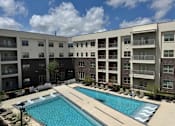 Thumbnail 2 of 21 - A large swimming pool in front of apartment buildings.