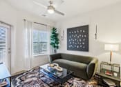Thumbnail 102 of 140 - Living room with olive green sofa and artwork at Matador Apartments, Austin, TX