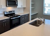 Thumbnail 9 of 21 - A kitchen with a stove, oven, microwave, and sink.