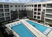 Thumbnail 10 of 21 - A large swimming pool in front of apartment buildings.