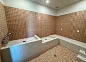Thumbnail 5 of 21 - A bathroom with brown tiled walls and a white bathtub.