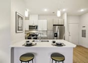 Thumbnail 106 of 140 - Modern kitchen with white island and pendant lights at Matador Apartments, Texas, 78745