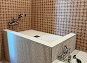 Thumbnail 6 of 21 - A white bathtub with a silver faucet and shower head in a bathroom with pink tiled walls.