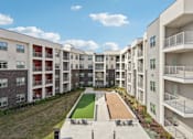 Thumbnail 95 of 103 - Central courtyard with bocce court and lawn at Cantarra Apartments, Manor, Texas