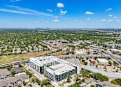 Thumbnail 61 of 127 - A large building with a green roof is surrounded by smaller buildings and houses.