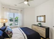 Thumbnail 111 of 140 - Bedroom with navy bedding and woven furniture at Matador Apartments, Austin