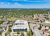 Thumbnail 63 of 127 - A large building with a green roof is surrounded by trees and other buildings.