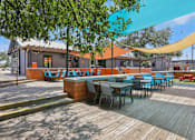 Thumbnail 82 of 116 - A wooden deck with tables and chairs is surrounded by trees. at Park South Apartments, Austin