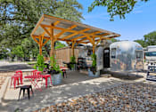 Thumbnail 85 of 116 - A wooden pergola is over a table with red chairs. at Park South Apartments, Austin, TX