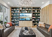 Thumbnail 73 of 127 - A living room with a large screen TV and a chandelier.