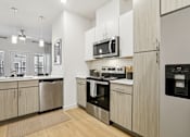 Thumbnail 8 of 140 - Kitchen with wood grain cabinetry and stainless appliances at Matador Apartments, Austin