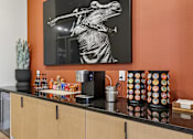 Thumbnail 79 of 127 - A kitchen with orange walls has a black and white photo of a man playing a guitar hanging on the wall.