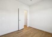 Thumbnail 131 of 140 - Empty bedroom with open door and wood flooring 1 at Matador Apartments, Texas