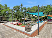 Thumbnail 96 of 116 - A wooden deck with a barrel and picnic tables. at Park South Apartments, Austin