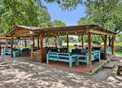 Thumbnail 97 of 116 - A wooden pavilion with blue benches is surrounded by trees. at Park South Apartments, Austin, Texas