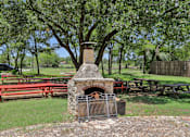 Thumbnail 98 of 116 - A stone fireplace is in the middle of a picnic area. at Park South Apartments, Texas, 78748