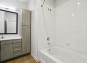 Thumbnail 135 of 140 - Bathroom with white tiled tub and tall cabinet at Matador Apartments, Texas