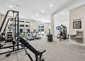 Thumbnail 89 of 127 - A gym with a variety of equipment including a squat rack, bench press, and a rowing machine.