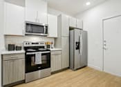 Thumbnail 10 of 140 - Kitchen with stainless refrigerator and white upper cabinets at Matador Apartments, Texas