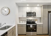 Thumbnail 52 of 116 - A modern kitchen with a stainless steel oven and a clock on the wall. at Park South Apartments, Austin, TX, 78748