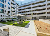 Thumbnail 100 of 127 - A patio area with a table and chairs is surrounded by apartment buildings.