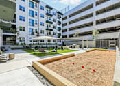 Thumbnail 101 of 127 - A sandbox with red balls in the middle of a concrete area surrounded by buildings.