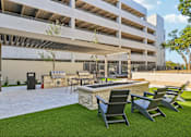 Thumbnail 103 of 127 - A patio area with chairs and a table in front of a parking garage.