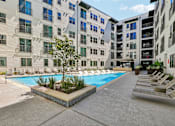 Thumbnail 114 of 127 - A pool surrounded by buildings and lounge chairs.
