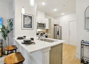 Thumbnail 12 of 140 - Modern kitchen island with white countertops and pendant lights at Matador Apartments, Austin, Texas