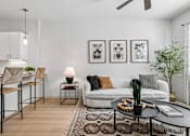 Thumbnail 35 of 127 - A living room with a white couch, a black coffee table, and a rug.