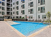 Thumbnail 116 of 127 - A swimming pool in front of a white apartment building.