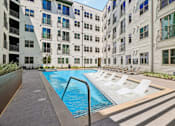 Thumbnail 117 of 127 - A swimming pool in front of a white building with a metal railing.