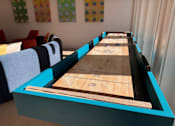 Thumbnail 57 of 83 - A shuffleboard table with blue and black trim is in the foreground of a room with colorful polka dot wall art. at ThreeTwenty at the Vybe Apartments, Texas, 78640