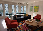 Thumbnail 58 of 83 - A living room with a black couch, a red chair, a wooden coffee table, and a colorful rug. at ThreeTwenty at the Vybe Apartments, Kyle, 78640