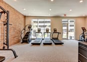 Thumbnail 16 of 46 - A gym with treadmills, elliptical machines, and a weight bench.